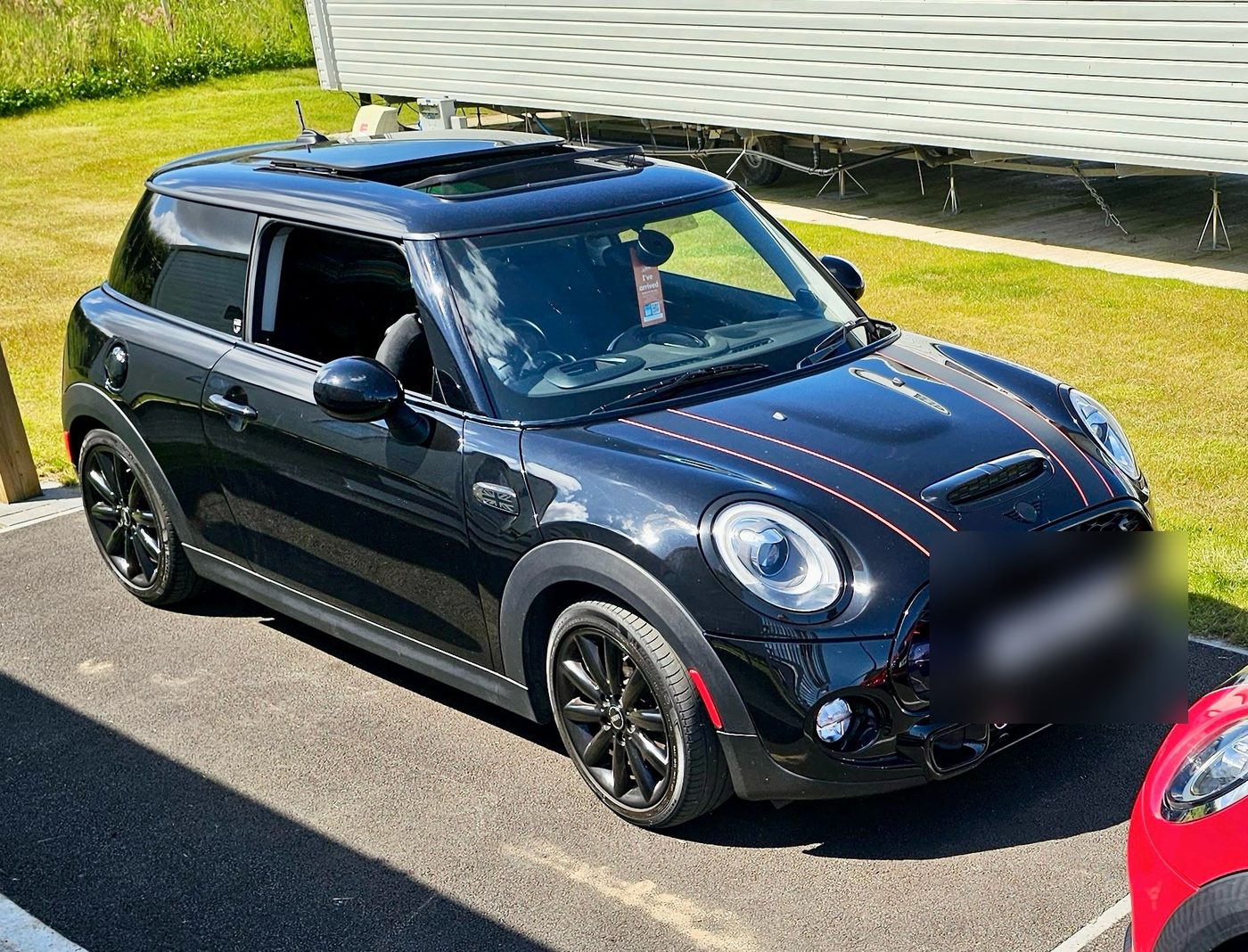 A black Mini Cooper with red bonnet stripes parked on Wilton Road